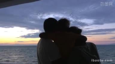 一家人抱着儿子拥抱着父亲和母亲在海上日落父亲抱着儿子在他的手上看从